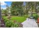 Relaxing backyard features a green lawn, garden beds, swing, and tiled patio at 19418 Morden Blush Dr, Lutz, FL 33558
