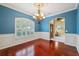 Elegant dining room featuring beautiful blue walls, dark hardwood flooring, wainscoting, chandelier and large window at 19418 Morden Blush Dr, Lutz, FL 33558