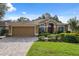 Charming single-story home boasts manicured lawn, brick driveway, and a warm-toned facade, creating a welcoming curb appeal at 19418 Morden Blush Dr, Lutz, FL 33558