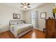 Cozy bedroom with hardwood floors, a comfortable queen-sized bed, a ceiling fan, and natural light from the window at 1987 Trillium Blvd, Brooksville, FL 34604
