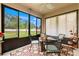 Enclosed lanai with ceiling fan, tile flooring, and view of the backyard featuring modern outdoor furniture set at 1987 Trillium Blvd, Brooksville, FL 34604