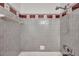 This shower features a hand held shower head and neutral colored tile walls at 2012 Warrington Way, Tampa, FL 33619