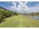 Serene backyard view, highlighting the lush green lawn, waterfront, and community homes beyond the yard at 3051 Francoa Dr, Odessa, FL 33556