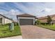 Charming single-story home with a brick driveway and well-manicured landscaping and gray garage door at 3051 Francoa Dr, Odessa, FL 33556