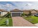 Charming single-story home with a brick driveway and well-manicured landscaping and gray garage door at 3051 Francoa Dr, Odessa, FL 33556