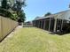 Backyard with green lawn, screened porch, partial pool fence, and privacy fence under a sunny sky at 3304 Honeymoon Ln, Holiday, FL 34691