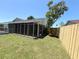 Backyard features well-maintained lawn, wooden fence, and screened-in porch for relaxing outdoor living at 3304 Honeymoon Ln, Holiday, FL 34691