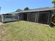 Green backyard features a partially fenced pool area and large screened-in porch, perfect for entertaining at 3304 Honeymoon Ln, Holiday, FL 34691