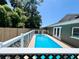 Backyard pool is surrounded by a white and wooden fence, with the house right next to the pool at 3304 Honeymoon Ln, Holiday, FL 34691