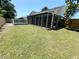 Lush backyard features a screened porch, wooden privacy fence, and partially fenced pool area at 3304 Honeymoon Ln, Holiday, FL 34691