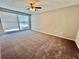 A large bedroom with neutral walls, carpet, ceiling fan, and natural light at 3304 Honeymoon Ln, Holiday, FL 34691