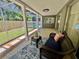 Relaxing screened-in patio with cozy seating, an area rug, and a view of the pool and backyard at 3304 Honeymoon Ln, Holiday, FL 34691