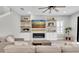 Open living room with fireplace, a ceiling fan, floating shelves, and a neutral color palette at 4056 Burdick Loop, Odessa, FL 33556