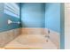 Bright bathroom with a white soaking tub surrounded by neutral tile and a window at 4094 Braemere Dr, Spring Hill, FL 34609