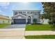 Inviting two-story home featuring a manicured lawn, attached two car garage, and gray exterior at 4094 Braemere Dr, Spring Hill, FL 34609
