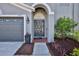 Close-up of front door with brick paver entry, flower arrangement, and attached two-car garage at 4094 Braemere Dr, Spring Hill, FL 34609