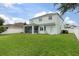 A spacious backyard featuring a screened porch, a well-maintained lawn, and a view of the two-story house at 4215 Maplehurst Way, Spring Hill, FL 34609