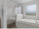 Bright bathroom featuring a glass shower and soaking tub under a frosted window at 4215 Maplehurst Way, Spring Hill, FL 34609
