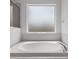 Close up of a clean, white bathtub with chrome fixtures and a frosted window at 4215 Maplehurst Way, Spring Hill, FL 34609