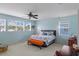 A blue-painted bedroom with ample natural light showcasing a king bed, ceiling fan and orange bench at 4215 Maplehurst Way, Spring Hill, FL 34609