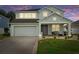 Charming two-story home with a well-manicured lawn and a welcoming front porch at dusk at 4215 Maplehurst Way, Spring Hill, FL 34609