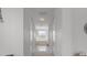 A hallway with white walls and trim that leads to a bright bathroom and a glimpse of the tub at 4215 Maplehurst Way, Spring Hill, FL 34609