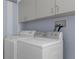This laundry room has a modern washer and dryer with white cabinets overhead at 4215 Maplehurst Way, Spring Hill, FL 34609