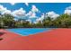 Bright blue community tennis courts with red surrounds, tall trees, and bright blue skies at 4215 Maplehurst Way, Spring Hill, FL 34609