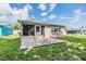 A home with a back patio with green grass and blue sky with clouds in the background at 4468 Rudder Way, New Port Richey, FL 34652