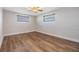 Bright, empty bedroom with hardwood floors, ceiling fan, and two windows for natural light at 4468 Rudder Way, New Port Richey, FL 34652