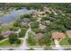 An aerial view captures the home nestled within a lakeside community with lush, mature trees at 4595 Lake In The Woods Dr, Spring Hill, FL 34607