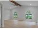 Bright bedroom with vaulted ceilings, wood beam, light wood floors, and arched windows framing the outdoors at 4595 Lake In The Woods Dr, Spring Hill, FL 34607