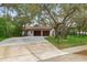 Charming home featuring a two-car garage, long driveway, and mature trees in a landscaped yard at 4595 Lake In The Woods Dr, Spring Hill, FL 34607