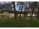 Attractive home exterior with a well-kept lawn and mature trees illuminated by outdoor lights at twilight at 4595 Lake In The Woods Dr, Spring Hill, FL 34607