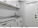 Bright laundry room featuring shaker cabinets, granite countertops and stainless steel faucet fixtures at 4595 Lake In The Woods Dr, Spring Hill, FL 34607
