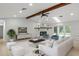 Spacious living room with a stone fireplace, wooden beam, and view of the backyard pool at 4595 Lake In The Woods Dr, Spring Hill, FL 34607