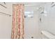 Bathroom shower with white tiled walls and an orange patterned curtain at 5642 Dove Dr, New Port Richey, FL 34652