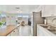 Bright kitchen view with a stainless steel refrigerator and tile flooring leading to a patio at 5642 Dove Dr, New Port Richey, FL 34652