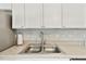 Stainless steel kitchen sink with a modern faucet, light countertop, and white cabinets at 5642 Dove Dr, New Port Richey, FL 34652