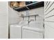 A laundry room features a white washer and dryer, shelf and box for storage at 5642 Dove Dr, New Port Richey, FL 34652