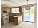 Bright kitchen area with white appliances, wood cabinets and a sliding patio door at 6406 Stone Rd, Port Richey, FL 34668