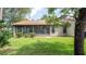 The back of a house featuring sliding glass doors to an enclosed patio and well-maintained lawn at 6620 Brambleleaf Dr, Spring Hill, FL 34606