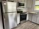 Kitchen showcasing stainless steel appliances, gray cabinetry, modern backsplash, and wood-look floors at 7104 Fair Ln, Hudson, FL 34667