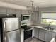 Bright kitchen featuring stainless steel appliances, gray cabinets, and a decorative backsplash at 7104 Fair Ln, Hudson, FL 34667