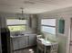 Charming kitchen with gray cabinets, stainless appliances, and a dining area near two windows at 7104 Fair Ln, Hudson, FL 34667