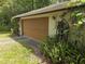 Exterior view of the garage showing the garage door, ferns and climbing vines at 7323 Ray Browning Rd, Brooksville, FL 34601