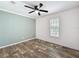 Bedroom featuring wood-look flooring, ceiling fan, natural light from the window, and a colorful accent wall at 7353 Thorpp Ave, Brooksville, FL 34613