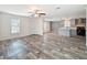Open-concept living room featuring modern wood-look flooring, ample natural light, and a ceiling fan at 7353 Thorpp Ave, Brooksville, FL 34613