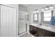 Well-lit bathroom featuring a double sink vanity, framed mirrors, and a glass-enclosed shower at 7523 Tangle Brook Blvd, Gibsonton, FL 33534