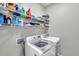 Functional laundry room features shelving, modern washer and dryer and neutral paint at 7523 Tangle Brook Blvd, Gibsonton, FL 33534
